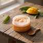 Close-up of Mango Salty Body Scrub jar on a rustic wooden surface, highlighting the frosted glass and vibrant label.